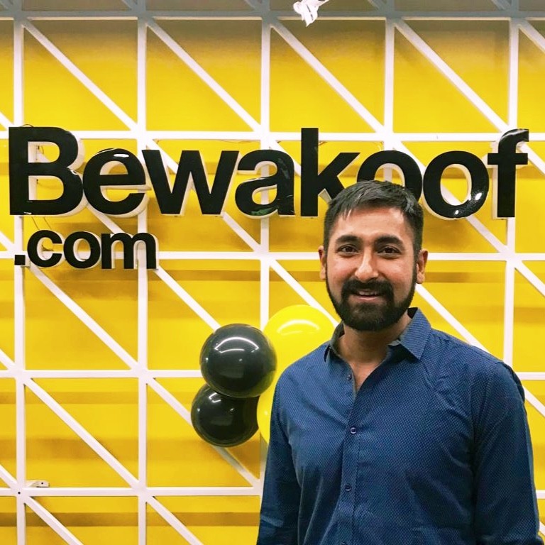 Man in blue shirt smiling at BeWakaoof.com office with yellow geometric wall and bowling balls